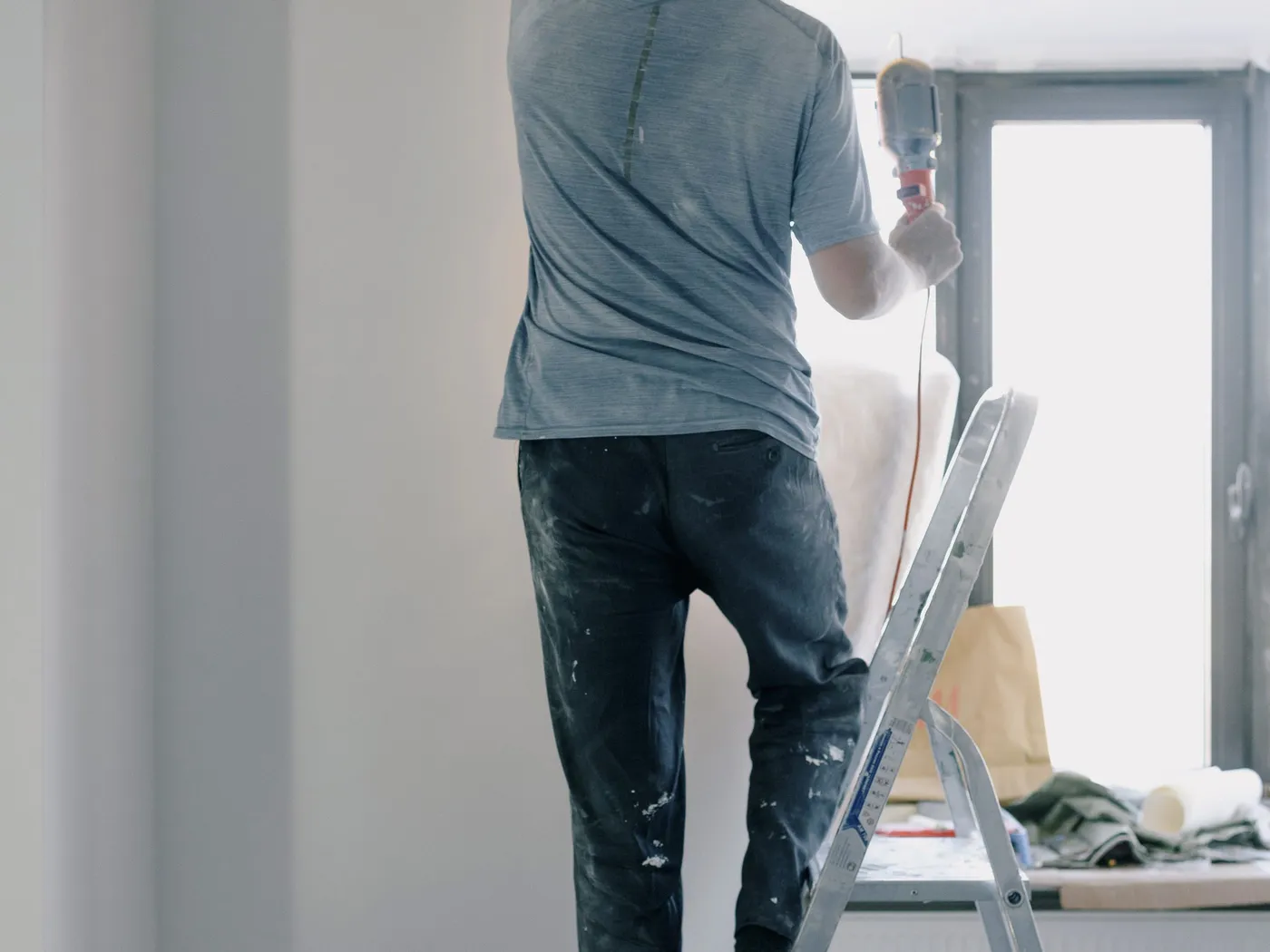A tradesperson on a stepladder working on a ceiling inside a home