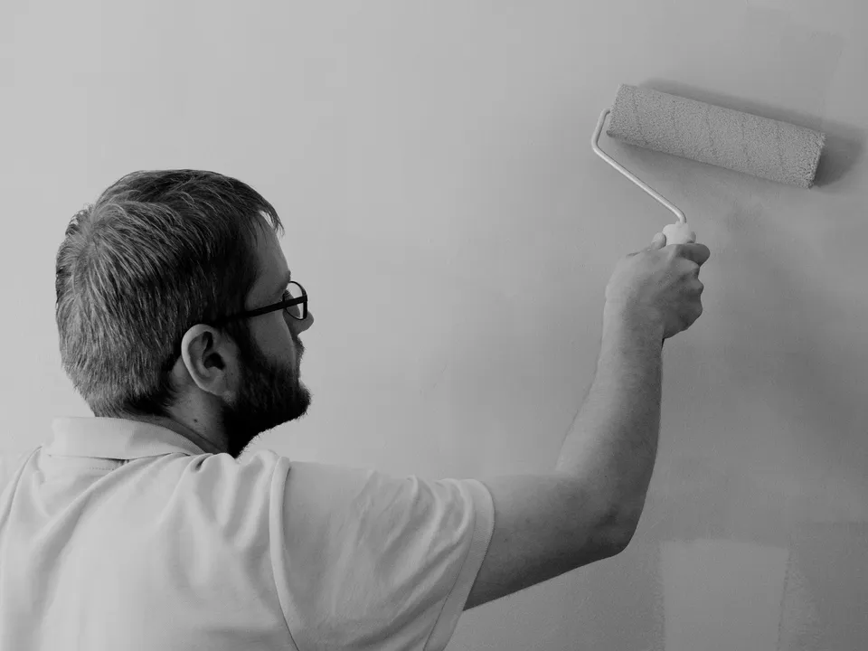 A decorator rolling fresh paint onto an interior wall