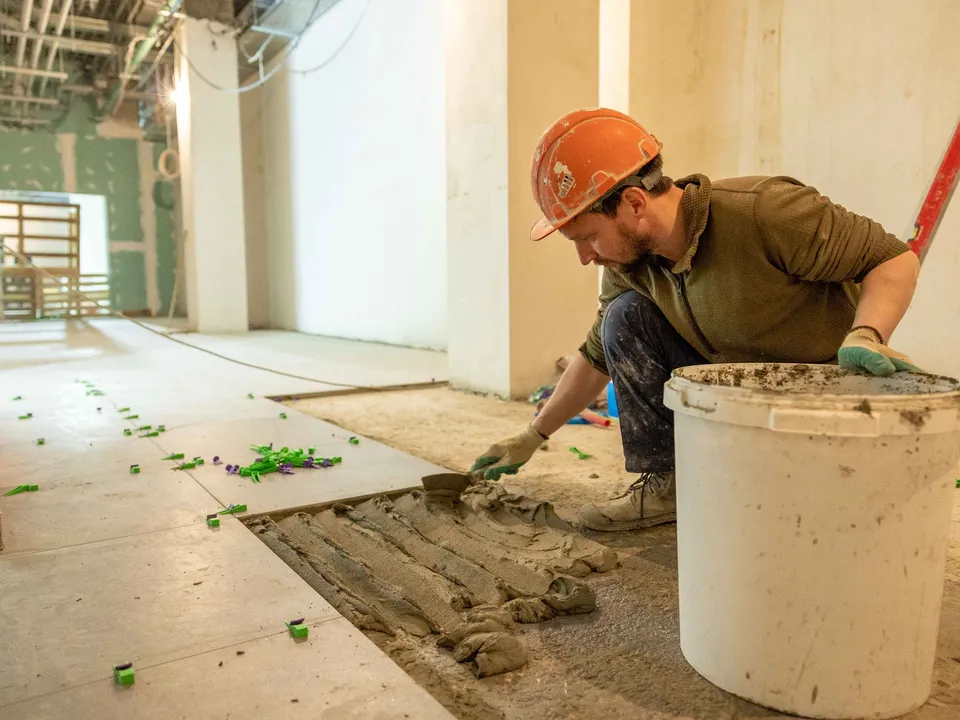 A tiler laying large floor tiles during a renovation