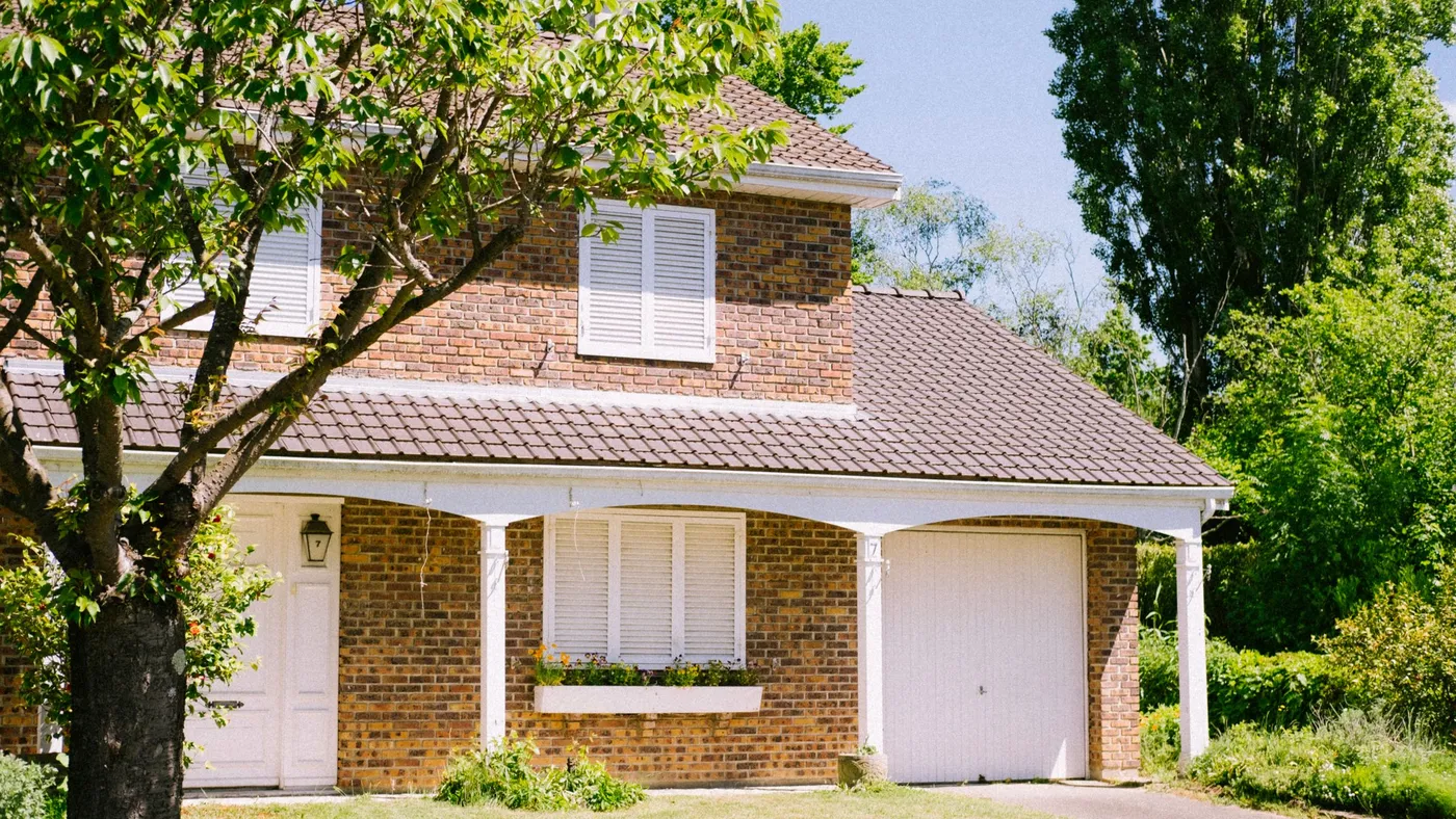 A two-storey brick house with a well-kept front garden on a sunny day