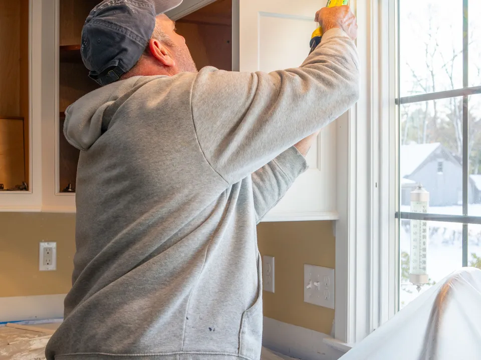 A fitter sealing the edge of a newly installed kitchen cabinet